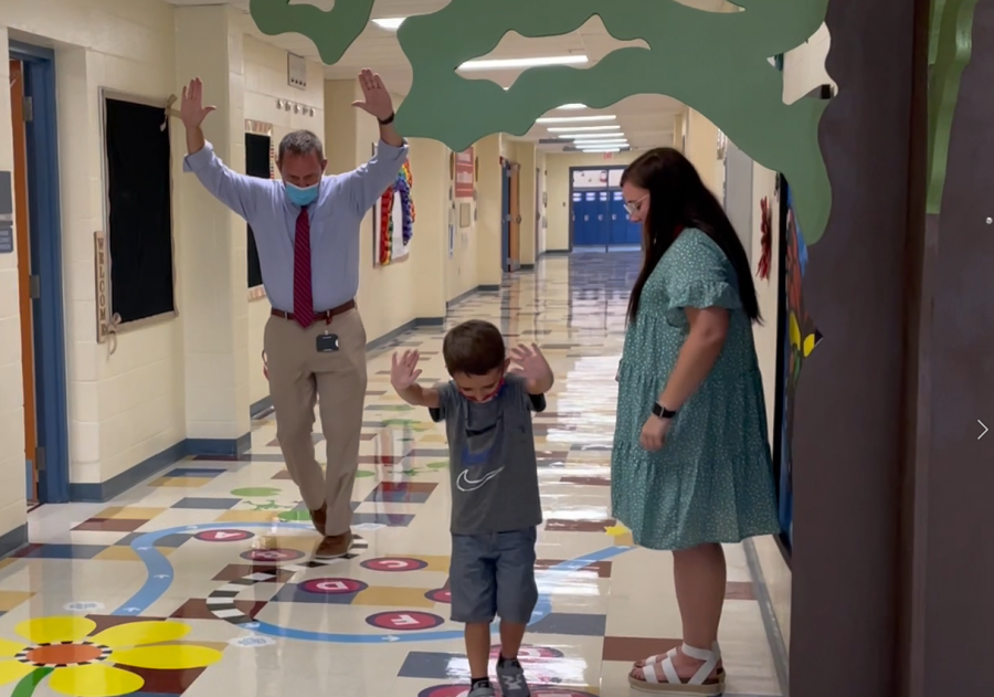  Mr. Sears plays hopscotch with a SLE student, both with their hands in the air in excitement.
