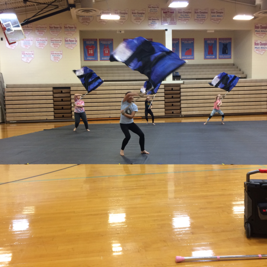 The Kings High School Guard spaces out on the gym floor to warm up and practice sections of the show. The gym floor is covered in a black tarp that they will perform on because they don’t have their show tarp yet. 
