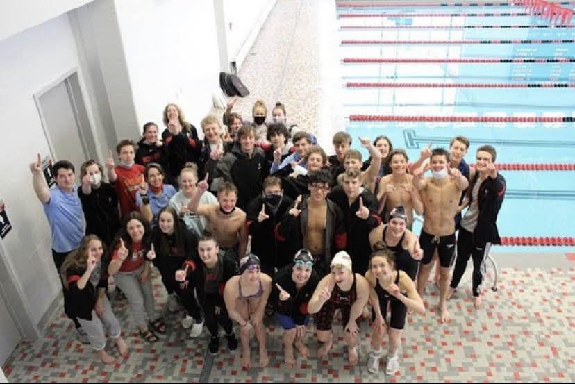 The Aqua Knights swim team throws up one finger in triumph, showing their place in the ECC meet.